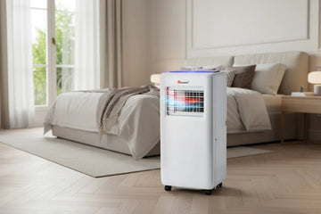 Deshumidificador portátil en dormitorio moderno, cerca de una cama y ventana luminosa.